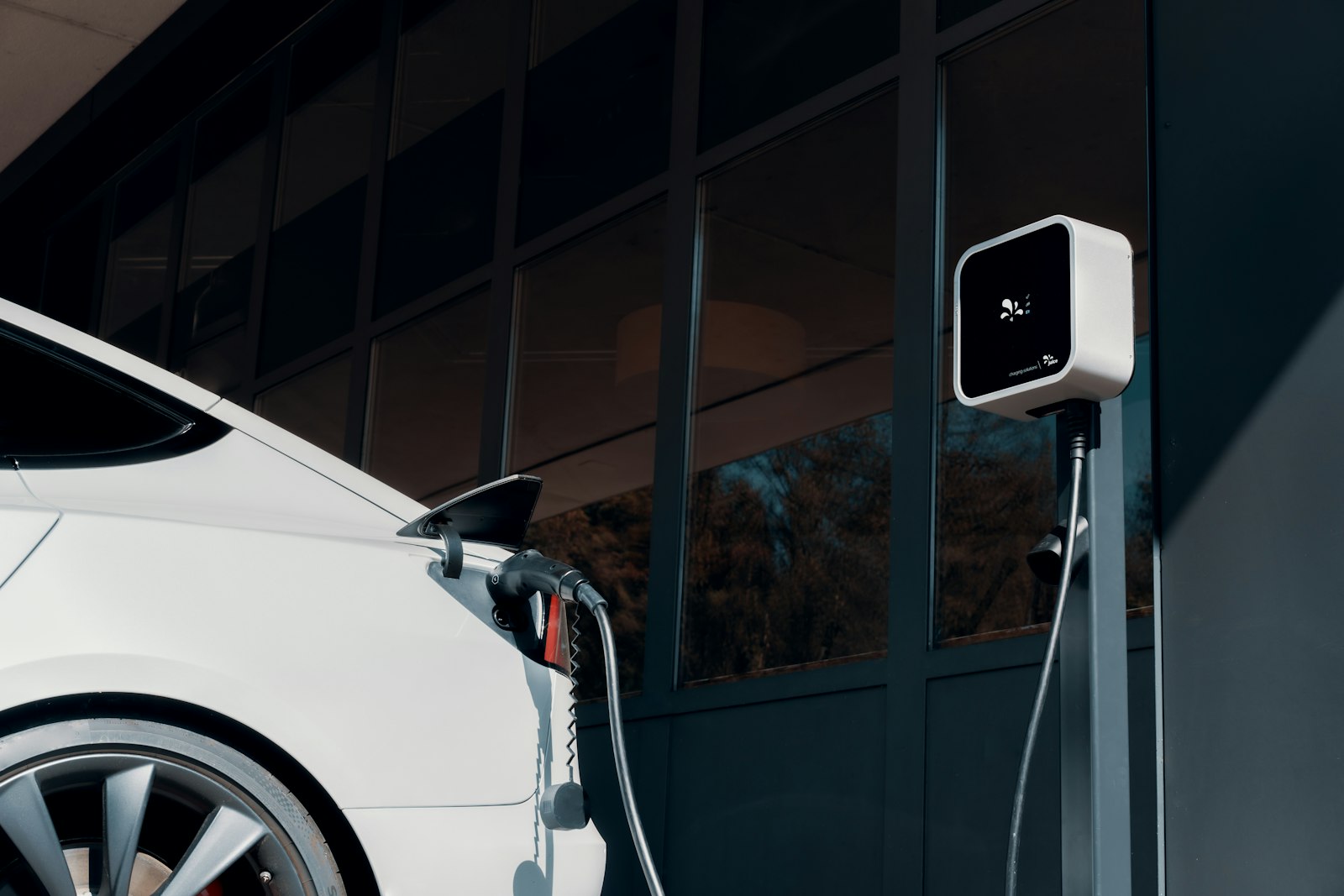 White electric vehicle plugged into a wall-mounted Level 2 charger